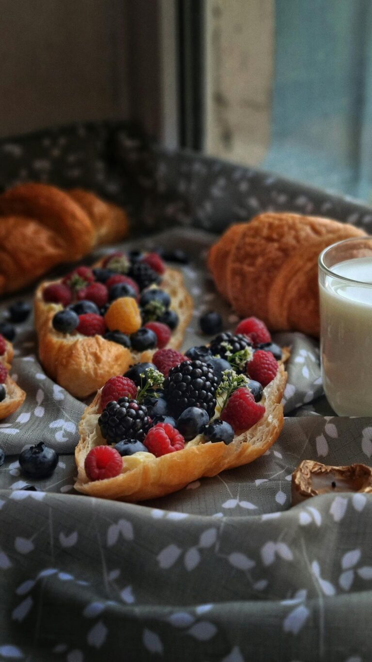 A cozy breakfast with croissants, fresh berries, and milk in soft natural lighting.