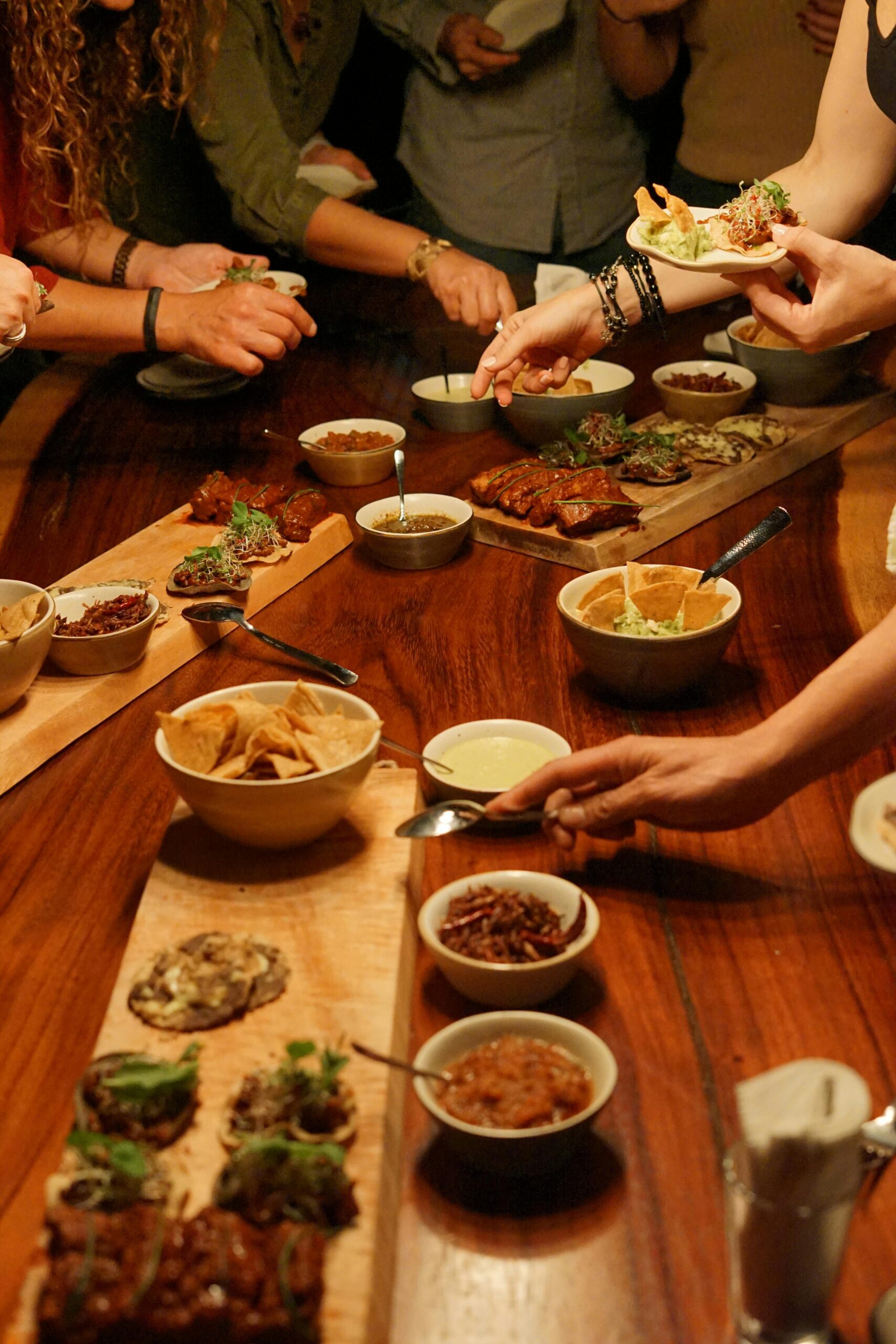 A lively dinner gathering with people enjoying shared plates of appetizers in a warm setting.